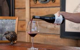 Hand pouring glass of Wet Jacket Pinot Noir