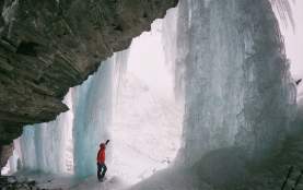Ice climber standing next to ice face