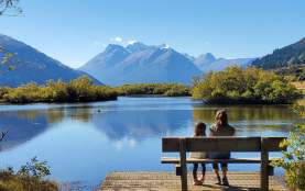Mum and daughter sitting by lake with view of mountains in the background