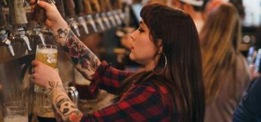 female bartender pouring beer into a glass at Mad Tree bar