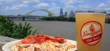 Plate of food and a beer in foreground on deck rail of Buckhead restaurant with view of Cincinnati
