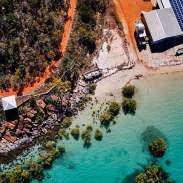 Overhead view of coastline at Cygnet Bay showing the red coloured pindan soil, white sand, turquoise waters as well as the mangroves and rocks