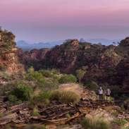 A couple standing on the rock formations in Mirima National Park at, with deepending pink colours in the sky