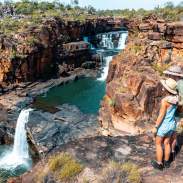 Hikers stand at the lookout point for Punamii-Unpuu (Mitchell Falls) with a view of three tiers of the falls
