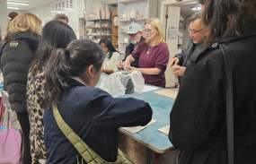 A group of people are gathered around a table working on making pinch pots with clay.
