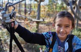 A girl is traversing the ropes course above the ground at Boundless Adventures.