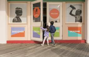 Two children are opening the door of the Westchester Children's Museum.