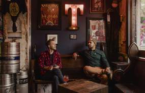 Two men sit together talking inside the Croton Tapsmith