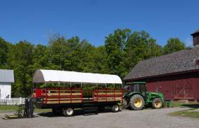 An accessible hayride wagon is attached to a green tractor.