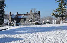 A building of the Tarrytown House Estate is in the background. The ground is covered with snow.