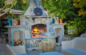 The outdoor dining area with a fire place, lighting and couch-style seating.