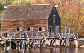 Philipsburg Manor building and bridge with yellow and orange fall leaves in the background.