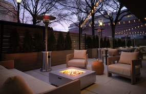 An outdoor patio at the Sonesta White Plains with a firepit and cushioned chairs.