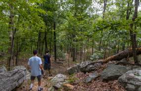 Two young men walk along a rocky trail at Ward Pound Ridge.