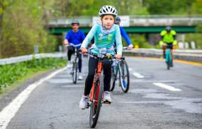 A girl rides her orange bike along the Bronx River Parkway.