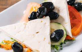 A dish with olives and tomatoes.