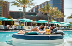 Two women relaxing on a bed, poolside