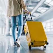 A person pulling a yellow roller suitcase in the airport.