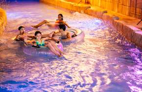 A family of four floating in a lazy river in Camelback Resort's indoor waterpark