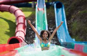 A young girl exits water slide with splashing water