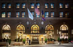 Exterior of a historic hotel with three flags hanging in front of the entrance