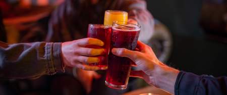 Three people clinking glasses in a dimly lit bar.