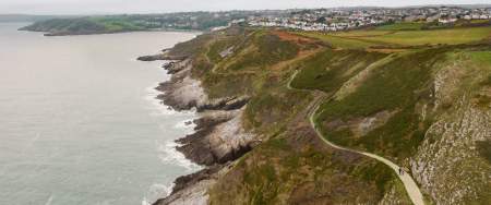 Drone shot of the rugged coastline of Gower with the coast path winding along.
