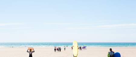 Surfers running down Llangennith Bay Beach