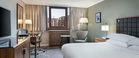 A contemporary hotel room with a bed, desk and TV.