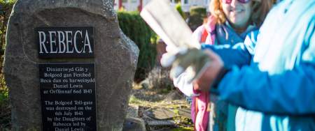Walkers looking at a stone with a plaque commemorating the Rebecca Rioters.