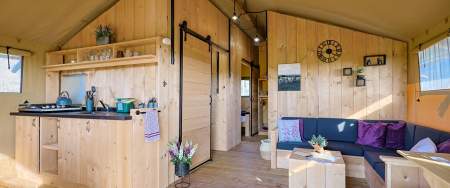 A wooden cabin with a kitchen and seating area.
