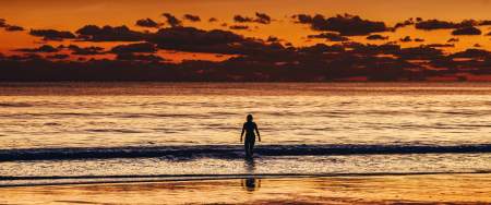 Sunset image of a person swimming at Caswell Bay