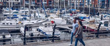 A man and woman walking around Swansea Marina.