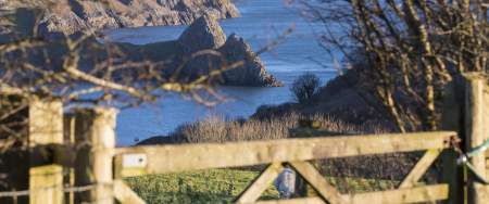 A gate in the countryside with Three Cliffs in the background.