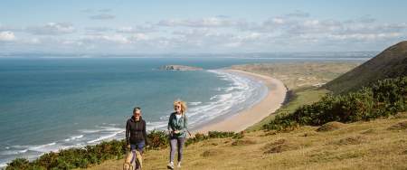 Two women walking a dog at Rhossili.
