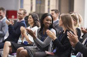 Attendees sitting in a meeting clapping