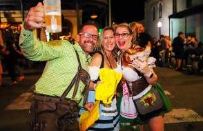 Two women and a man holding a beer bug and a pretzel