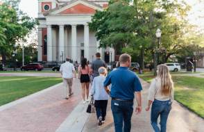 Men and women walk together on a sidewalk towards a large church