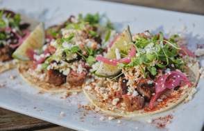 Plate of open-faced tacos with garnish on table