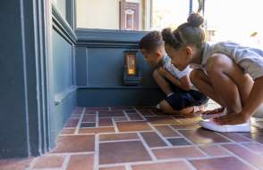 Two children kneeling down to look in a fairy door