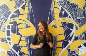 Woman smiling in front of U-M Wings Mural