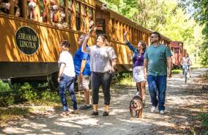 People enjoying a beautiful day walking alongside the steam engine on the heritage rail trail