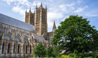 Sunny day exterior of Lincoln Cathedral with trees in the foreground