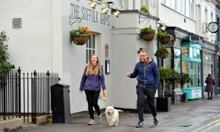 People walking a dog through The Suffolks in Cheltenham.