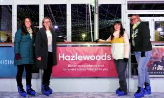 Hazlewoods team next to the Hazlewoods ice rink board at Cheltenham Ice Rink.