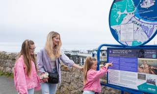 Family looking at Llandudno Heritage trail board