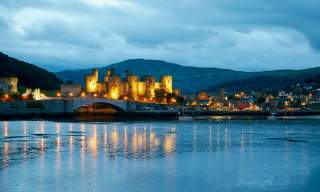 A view across the water of Conwy Castle at night, lit up