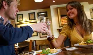 Two people toasting drinks in a bar