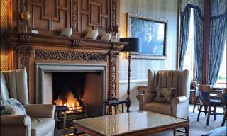 a lounge with open fire armchairs and sofa in Bovey Castle