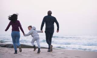 family running on a beach in winter